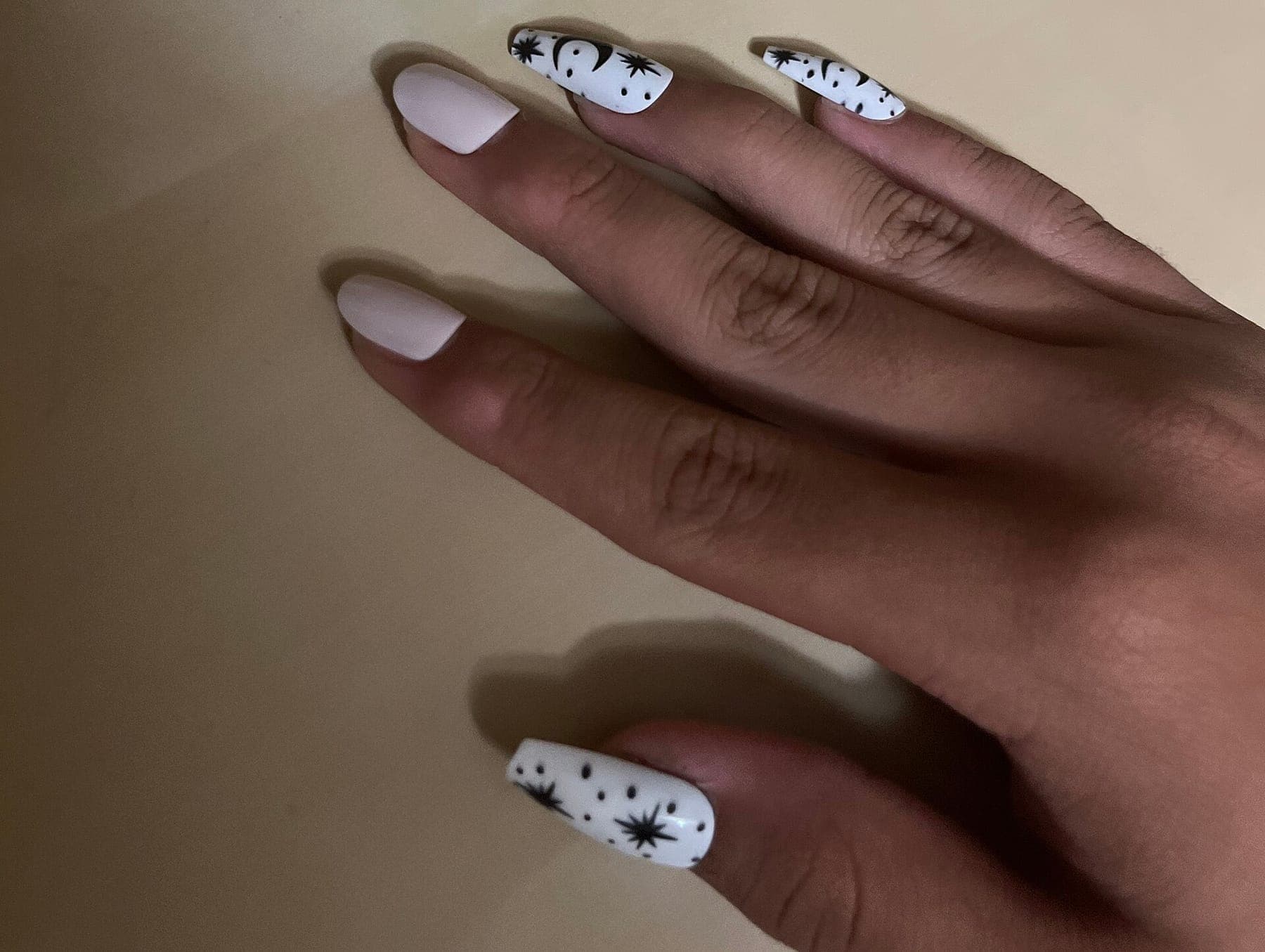 Almond-shaped nails in soft white with black star and moon detail